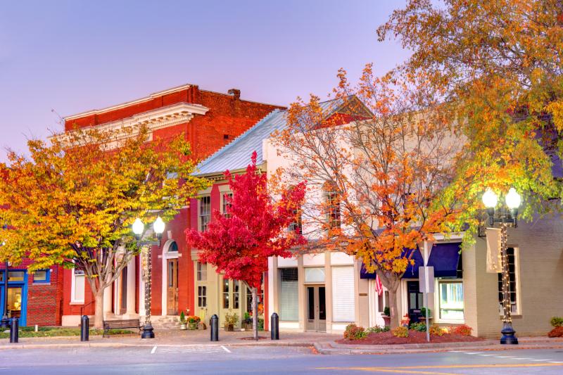 Red storefront buildings with autumn trees along a small-town street